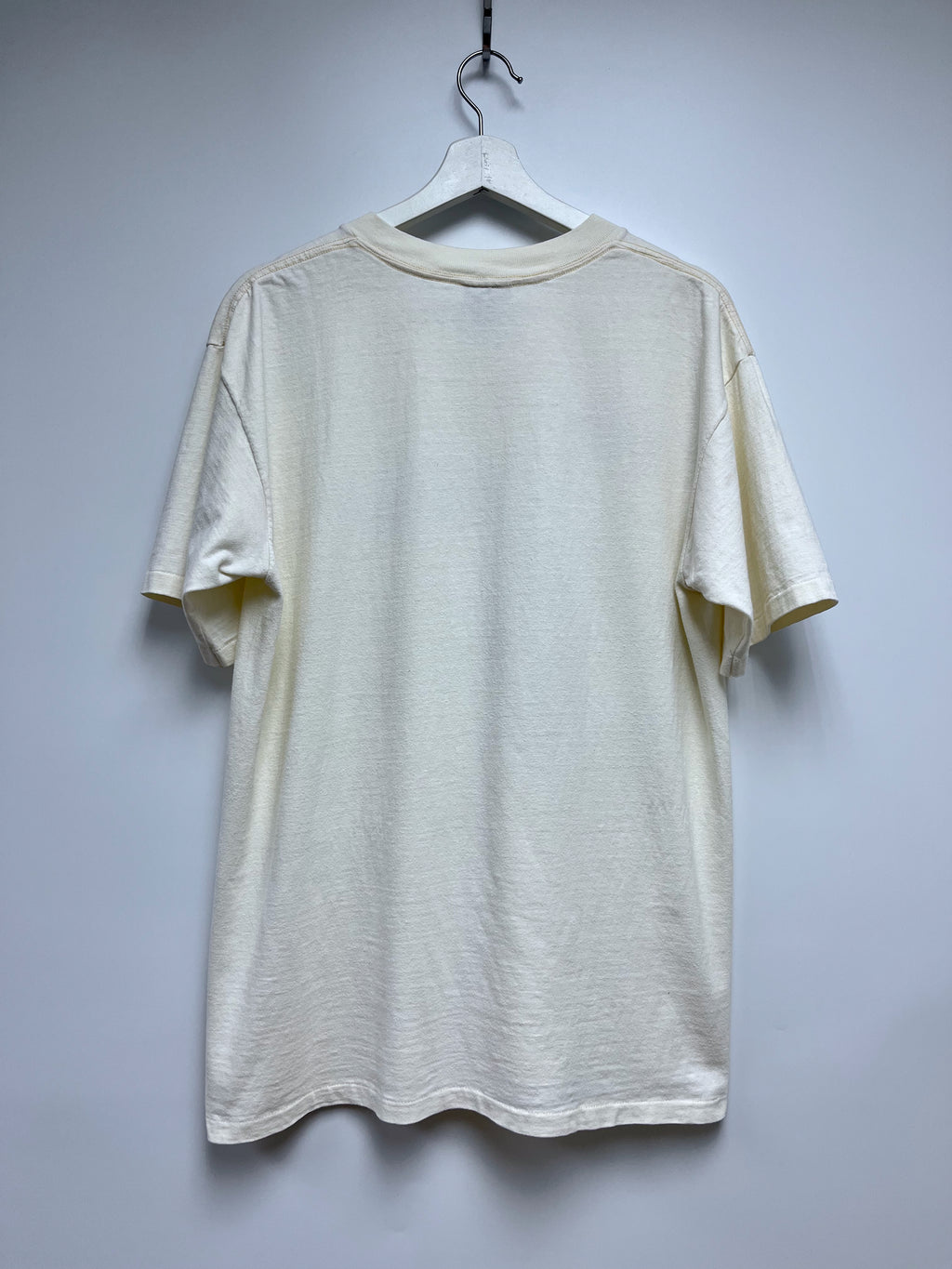 Beige t-shirt on a hanger against a plain background