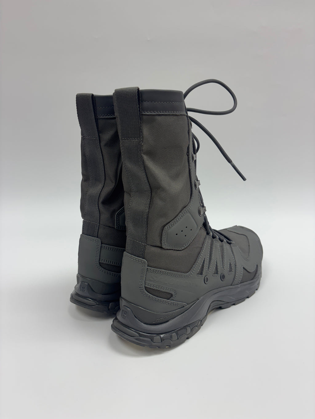A pair of dark gray tactical boots shown from a three-quarter rear angle against a light gray studio background.
