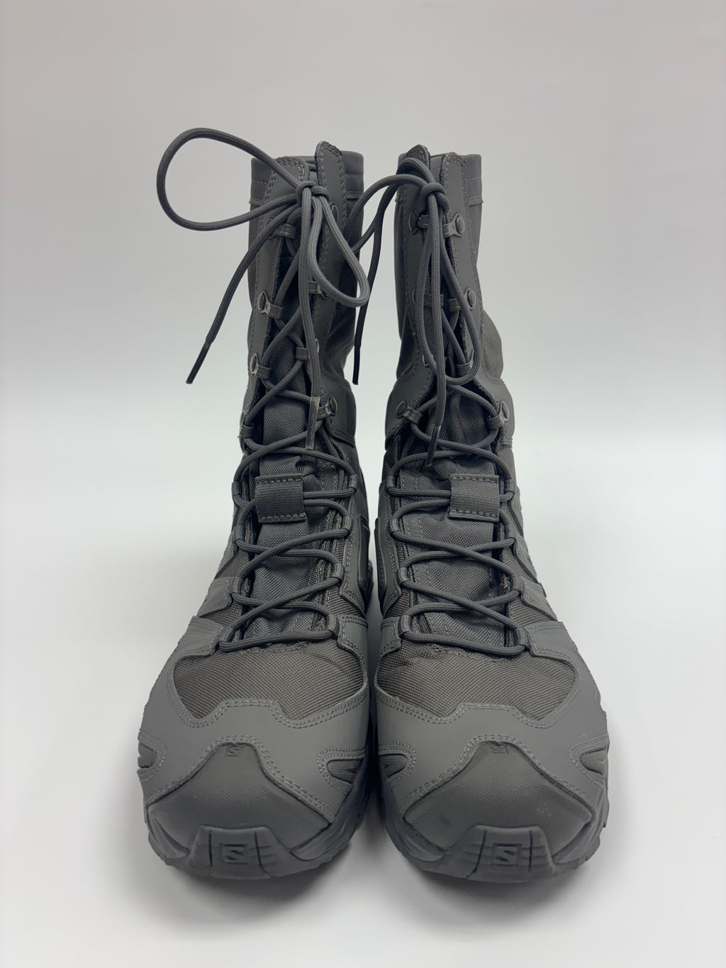 A pair of dark gray tactical combat boots with matching laces, photographed from the front against a light gray studio background.