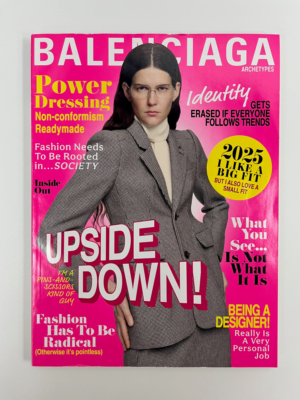 Balenciaga magazine cover with a model wearing a gray suit against a pink background