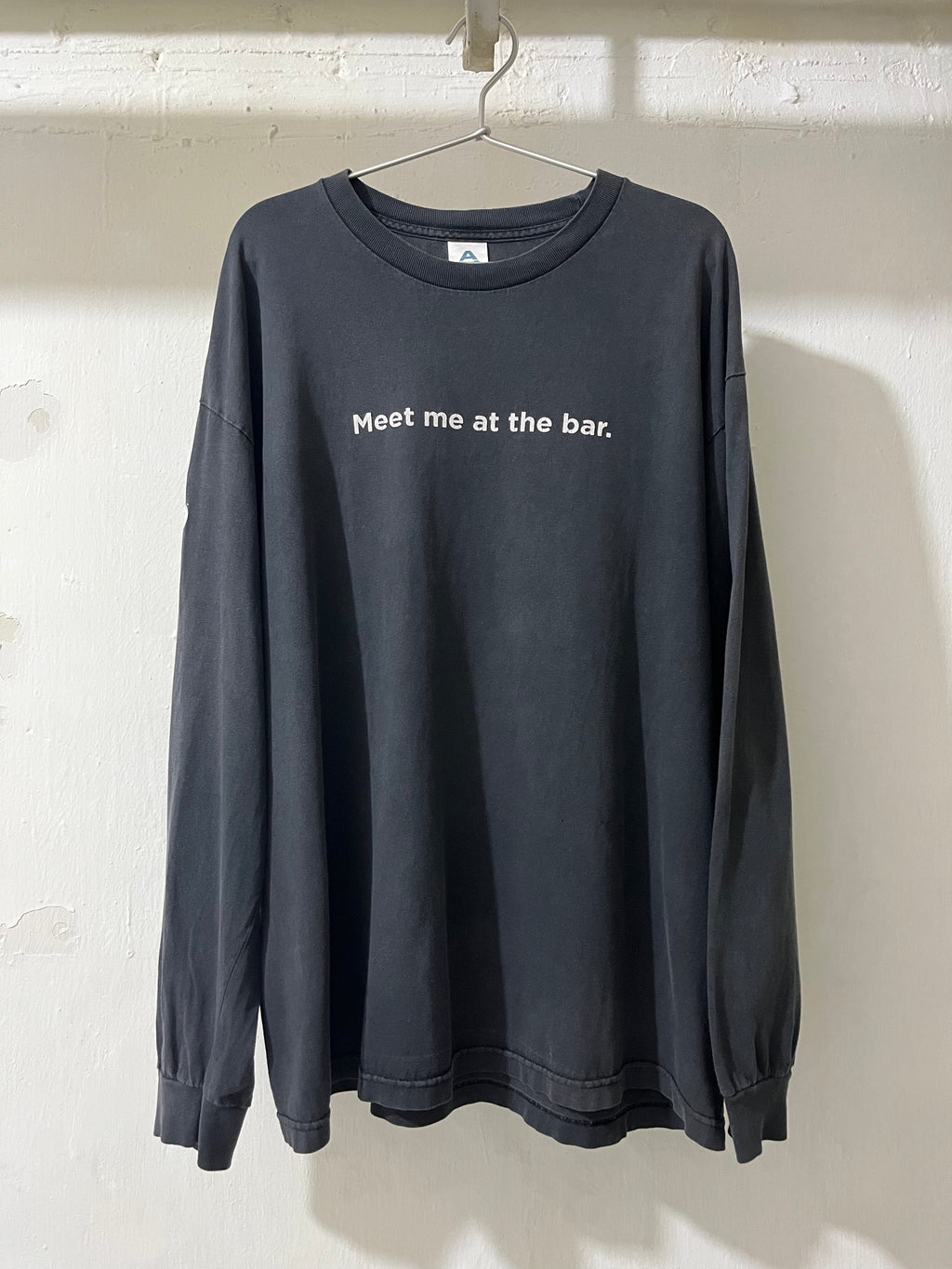 Black long-sleeve shirt with 'Meet me at the bar.' text on a white background