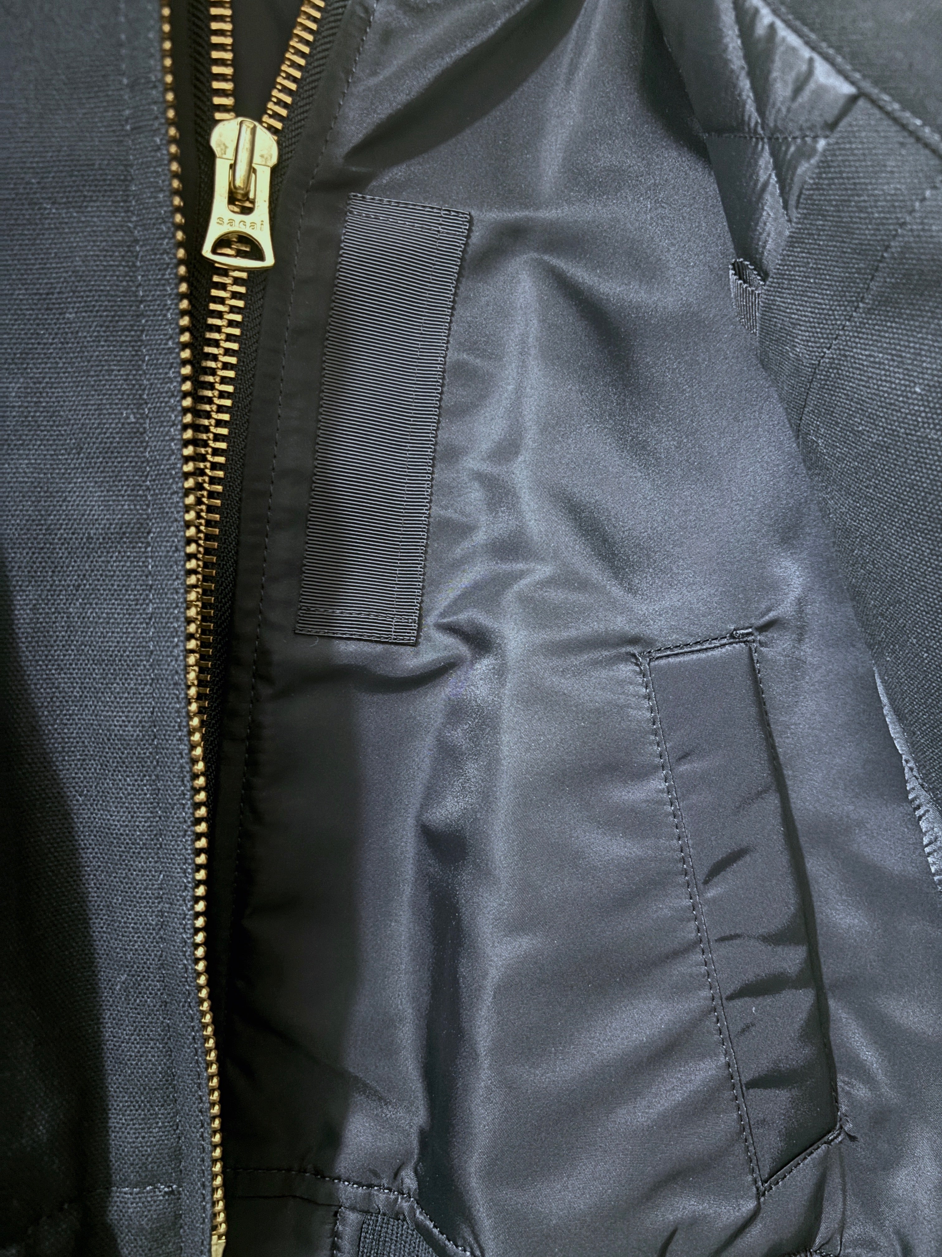 Close-up of a dark gray jacket with a gold zipper