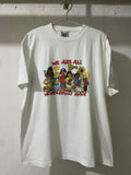 A white short-sleeve graphic t-shirt hanging on a metal hanger against a white painted brick wall. The front of the shirt features a colorful cartoon illustration of diverse children and the text 'WE ARE ALL WONDERFULLY MADE' in red.