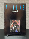Movie pROGRAM for 'Aliens' with a character holding a weapon on a textured gray background