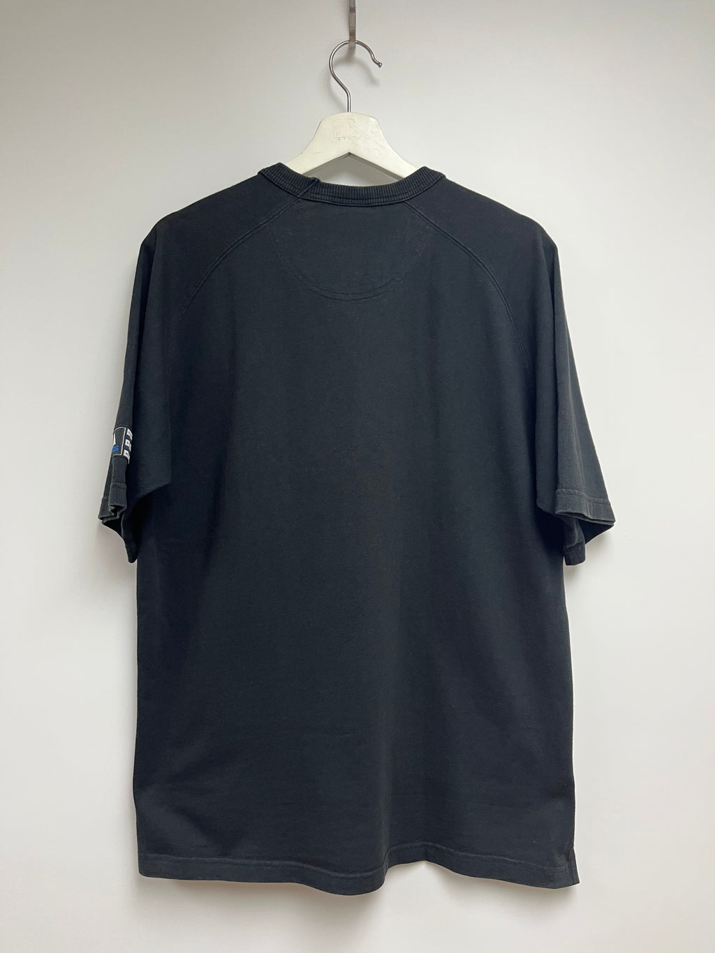 Black t-shirt on a hanger against a white wall